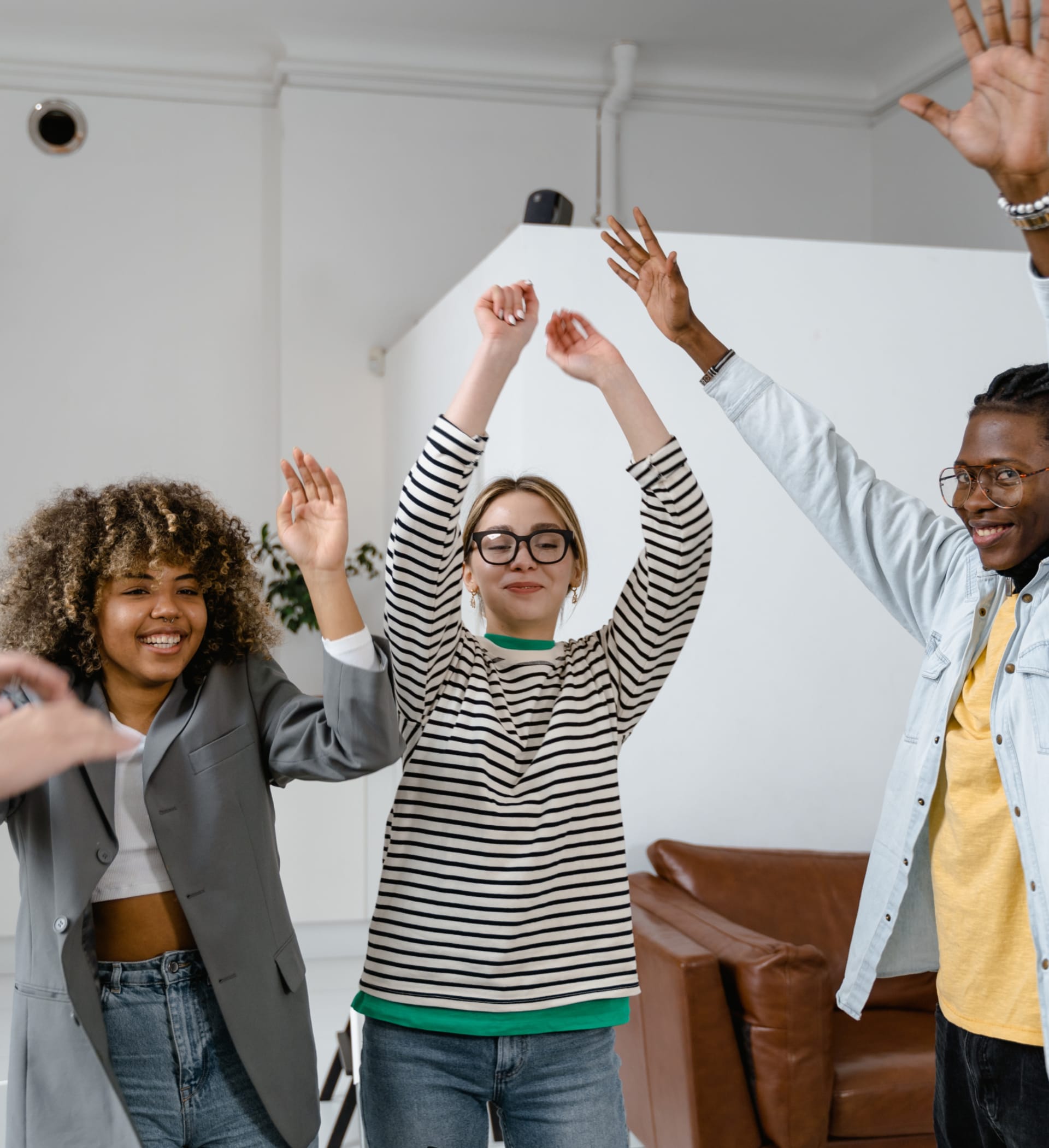 Three young people in a semi circle with their arms raised, celebrating